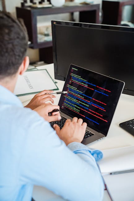 A close-up image of a computer screen displaying lines of multi-colored programming code, featuring keywords, variables, and functions in shades of red, blue, green, yellow, and white on a dark backgr